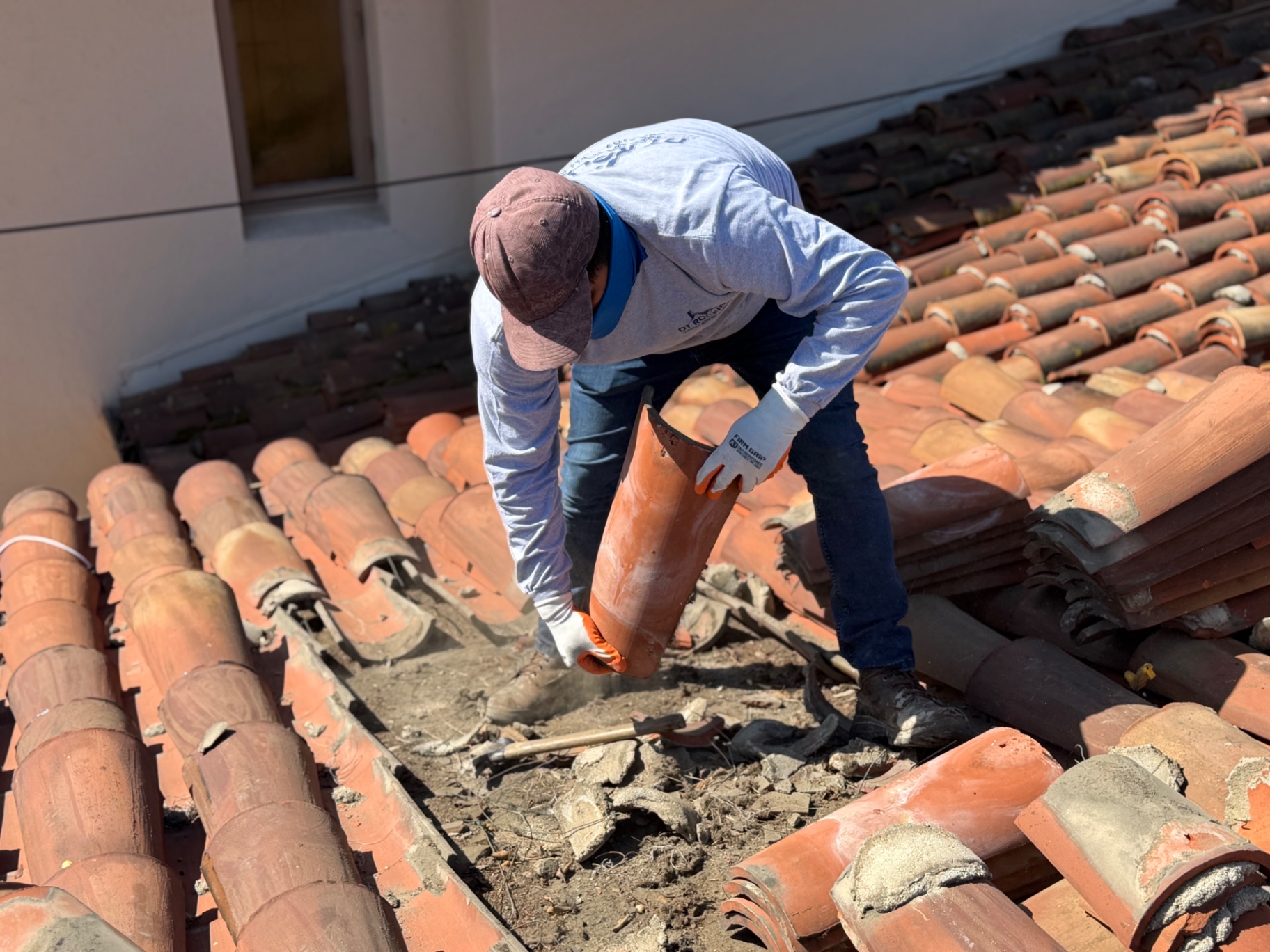 Roofer relaying clay tiles on a tile roof restoration
