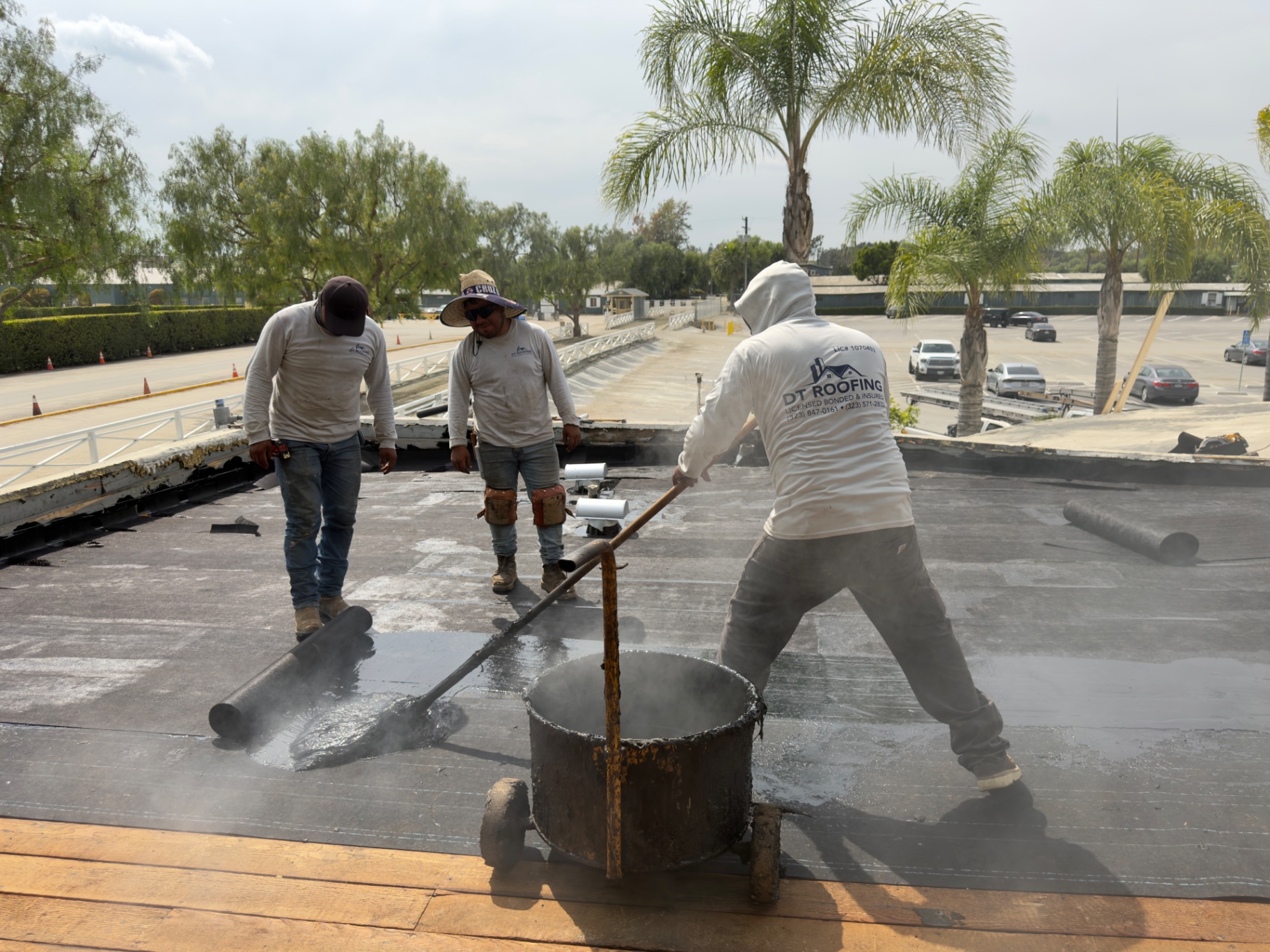 DT Roofing crew applying hot asphalt during a built-up roof installation